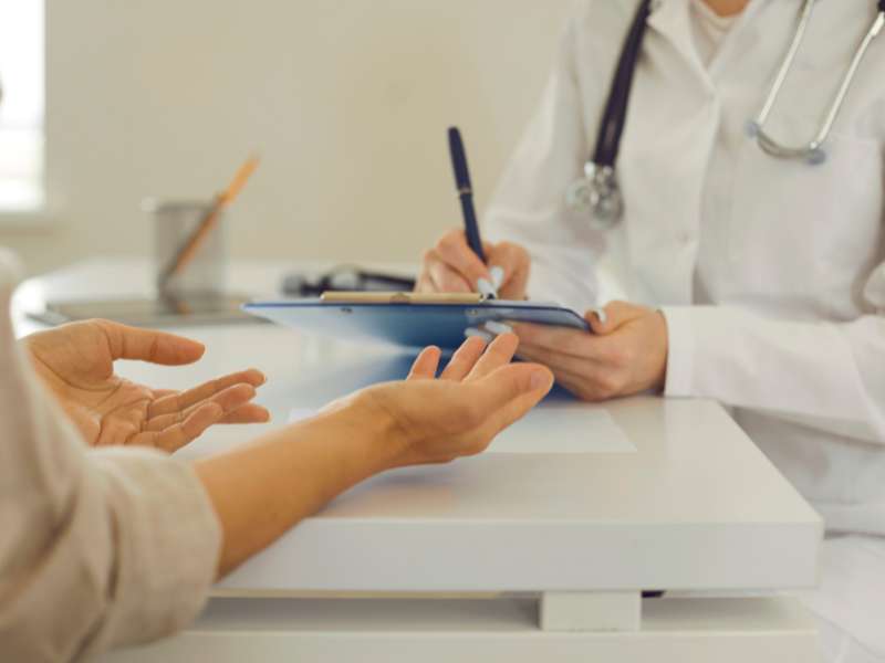 médica conversando com um paciente em um consultório